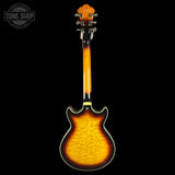 A classic electric guitar shown from the back, featuring a vibrant sunburst finish that transitions from bright yellow-orange in the center to dark brown and black around the edges. The headstock is visible at the top, and the guitar is photographed against a solid black background with a 'TONE SHOP' watermark in the upper left corner.