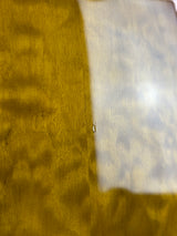 A close-up of a textured golden yellow surface with a glossy, reflective white section at the top.