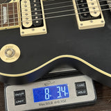 Black electric guitar on a digital scale displaying weight