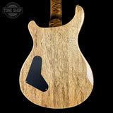 The back of an electric guitar with a natural wood grain finish and a black pickguard, shown against a solid black background with a Tone Shop watermark in the top left corner.