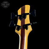 Close-up of a bass guitar headstock with a black background and 'Tone Shop' logo.