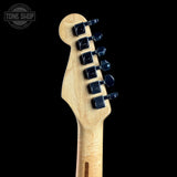Close-up rear view of a natural wood electric guitar headstock with six black tuning pegs against a solid black background.