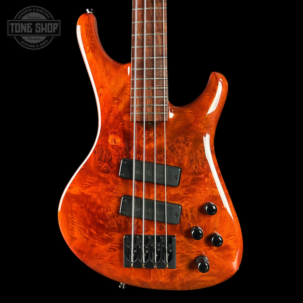 Orange electric bass guitar with a black background, featuring the Tone Shop logo.