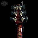 Close-up of the headstock of a guitar against a black background, showing six tuning pegs, a dark reddish-brown flamed maple finish, and a Tone Shop watermark in the upper left corner.