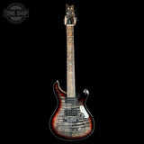 A double-cutaway electric guitar with a flamed maple top featuring a dark brown to black sunburst finish, shown against a solid black background. A Tone Shop watermark is visible in the upper left corner.