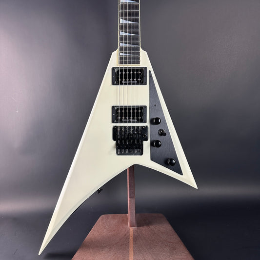 White electric guitar on a stand against a dark background