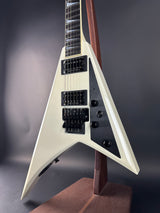 Close-up of a white electric guitar with a unique body shape on a dark background