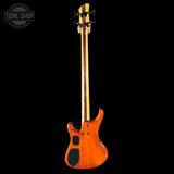 Electric bass guitar with a wooden finish on a black background, featuring the Tone Shop logo.