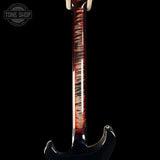 Close-up of the neck of an electric guitar with a glossy flamed maple finish showing red, brown, and black swirls, set against a solid black background. A Tone Shop watermark is visible in the top left corner.