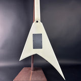 White guitar body on a stand against a dark background