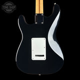 The back of a black electric guitar with a maple neck, chrome hardware, and a white pickguard, shown against a black background with a Tone Shop watermark in the top left corner.