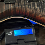 A close-up of a guitar body with a digital smart weigh scale placed underneath it to measure the weight of the instrument.