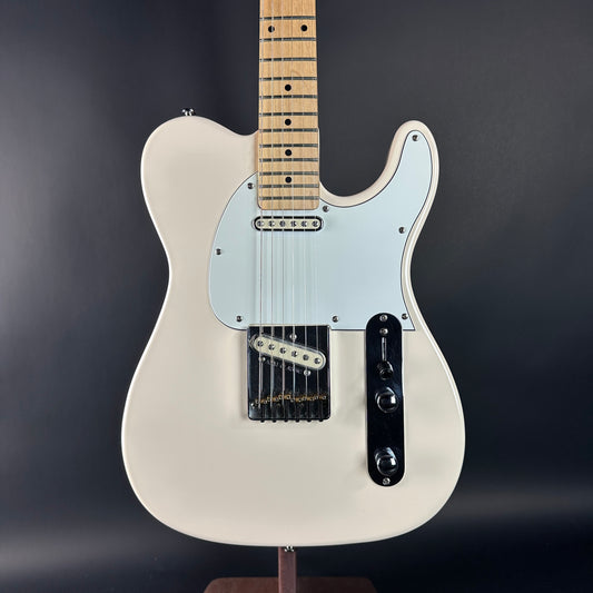 White electric guitar on a stand against a dark background