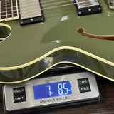 Green electric guitar on a digital scale displaying weight.