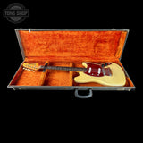 A cream-colored electric guitar with a dark red pickguard and black headstock, displayed inside an open orange-lined hard case on a black background. A Tone Shop watermark is visible in the top-left corner.