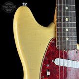 Close-up of a classic electric guitar body, showing a yellowed single-cutaway shape with a red marbled pickguard and part of the dark fretboard. A Tone Shop watermark is visible in the top-left corner.