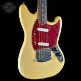 A vintage-style electric guitar with a cream-colored body, a red glittery pickguard, and a dark fretboard, shown against a solid black background.