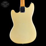 The back view of a vintage Fender Telecaster electric guitar with a cream-colored body and a natural wood neck, shown against a solid black background.