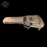 A tan acoustic guitar gig bag with black zippers and straps, featuring a front pocket with 'SE' and 'SOUND ENGINEER' printed on it, shown against a solid black background.