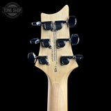 Close-up of the headstock of a guitar, showing six black tuning pegs and printed specifications on a black background. A Tone Shop watermark is visible in the top left corner.