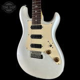A white electric guitar with a cream pickguard and dark fretboard, shown against a solid black background. A Tone Shop watermark is visible in the top-left corner.