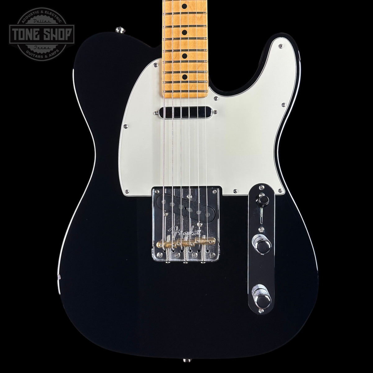 A black electric guitar with a white pickguard and maple fretboard, shown from the front against a black background. A Tone Shop watermark is visible in the top-left corner.