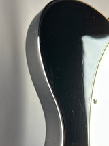 Close-up of a glossy black electric guitar body with a white edge and a small visible screw near the top.