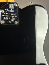 Close-up of the back of a glossy black Fender electric guitar body, showing the control plate with Fender branding and screws.