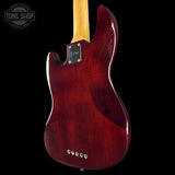 Red electric guitar with a wooden neck on a black background, featuring 'Tone Shop' branding.