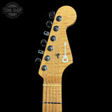 Close-up of an electric guitar headstock with a natural maple wood finish, six black tuning pegs, and a white 'Tone Shop' logo, shown against a solid black background.