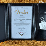 Fender certificate of authenticity in a black leather case on a gold textured surface