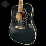 Black acoustic guitar with decorative inlay on a black background, featuring the Tone Shop logo.