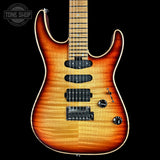 A double-cutaway electric guitar with a natural flame maple body, fading from a bright honey-orange center to a dark brown edge, shown against a solid black background.