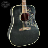 Black acoustic guitar with decorative inlay on a black background, featuring 'Tone Shop' logo.