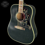 Black acoustic guitar with decorative inlay on a black background, featuring 'Tone Shop' logo.