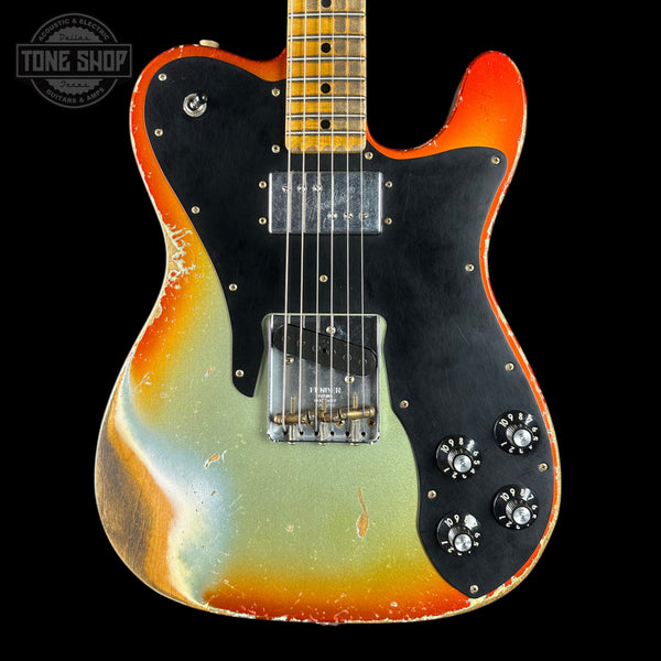 Electric guitar with a multicolored body on a black background, featuring the Tone Shop logo.