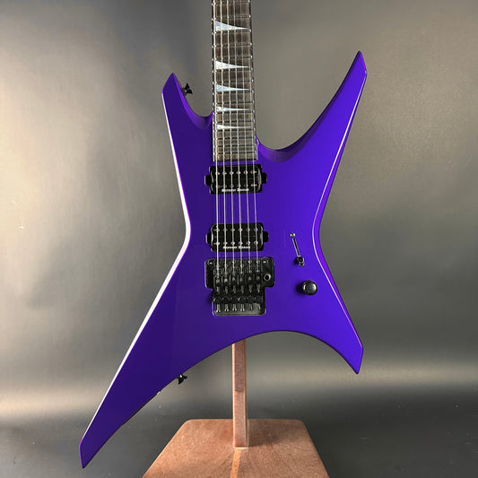 Purple electric guitar on a stand against a gray background