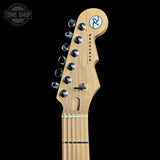 Close-up of the headstock of a guitar with a natural maple wood finish, chrome tuning pegs, and a circular logo sticker on a black background.