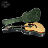 Acoustic guitar in a hard-shell case with 'Tone Shop' logo.