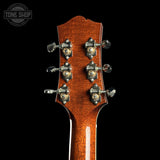 Close-up of a guitar headstock with tuning pegs on a black background, featuring the Tone Shop logo.