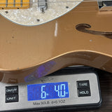 Gold electric guitar on a digital scale displaying weight.