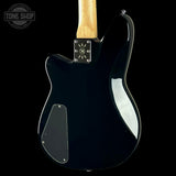 Rear view of a black electric guitar with a natural wood neck and chrome hardware, shown against a solid black background.