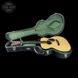 Acoustic guitar in a hard-shell case with 'Tone Shop' logo.