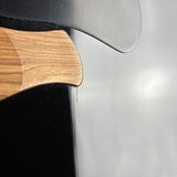 Close-up detail of a kitchen knife showing a polished wood handle and a dark metallic blade against a reflective gray background.