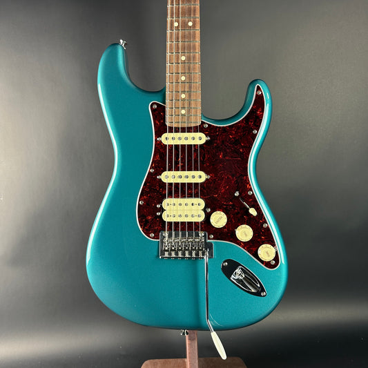 Blue electric guitar on a stand against a gray background