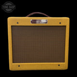 Yellow Fender Champ guitar amplifier with tweed front panel on a black background