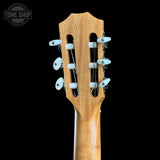 Close-up of the headstock of a classical guitar with a natural wood finish and white tuning pegs, shown against a solid black background with a Tone Shop watermark in the top left corner.
