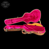Open guitar case with pink interior on a black background, featuring 'Tone Shop' logo.