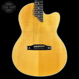 Acoustic guitar with a natural wood finish on a black background, featuring the Tone Shop logo.