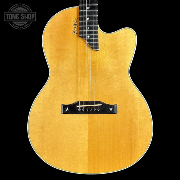 Acoustic guitar with a natural wood finish on a black background, featuring the Tone Shop logo.